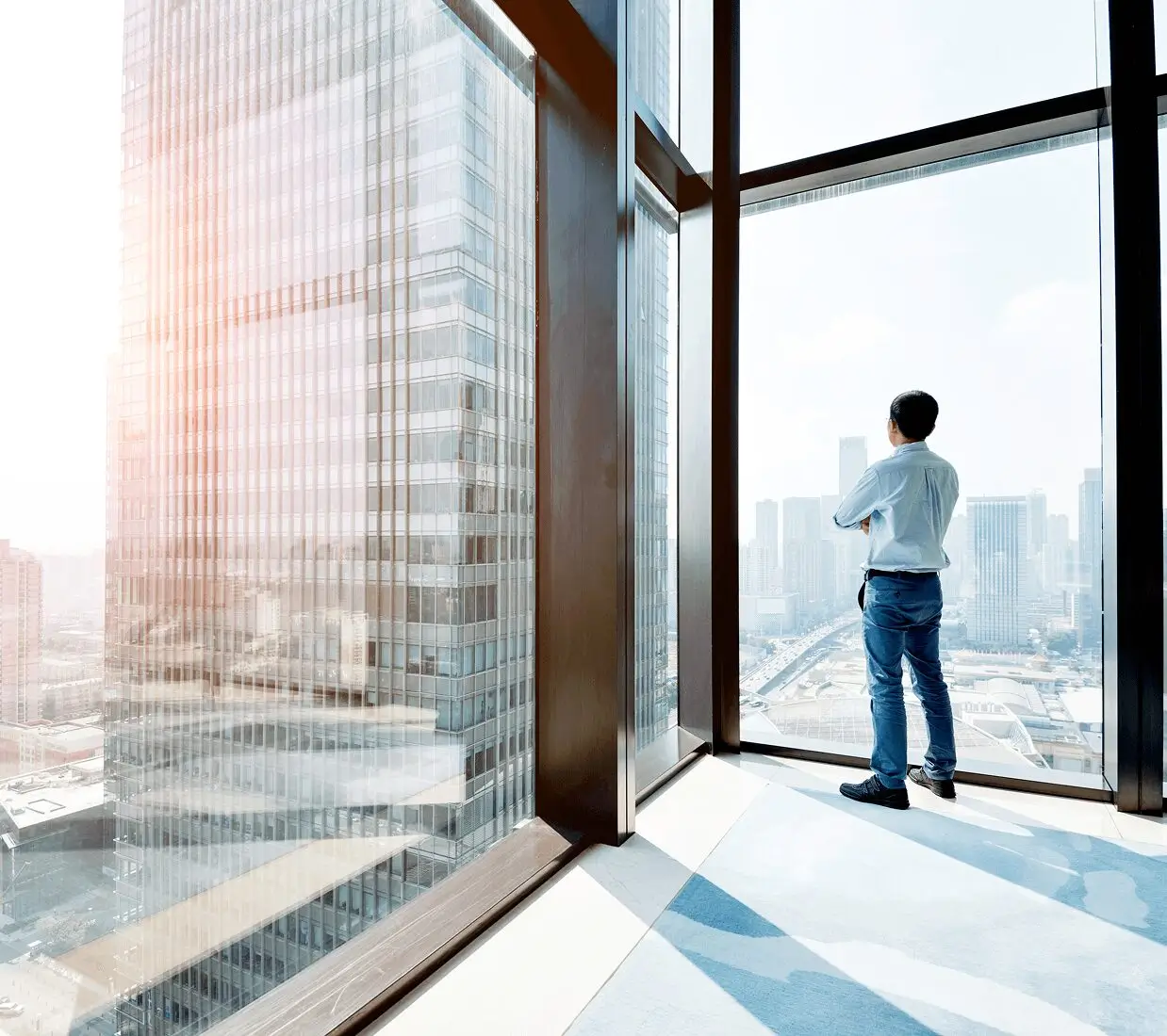 Person looking out a large window cityscape.